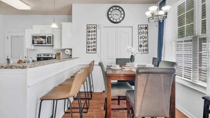 Una cocina moderna con microondas, estufa y comedor con sillas y una mesa.