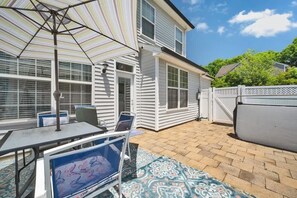 Une terrasse avec une table et des chaises, un parasol à rayures et un tapis à motifs.
