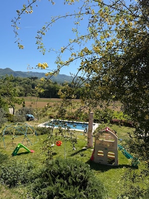 A backyard with a swimming pool, a playhouse, and a climbing structure.