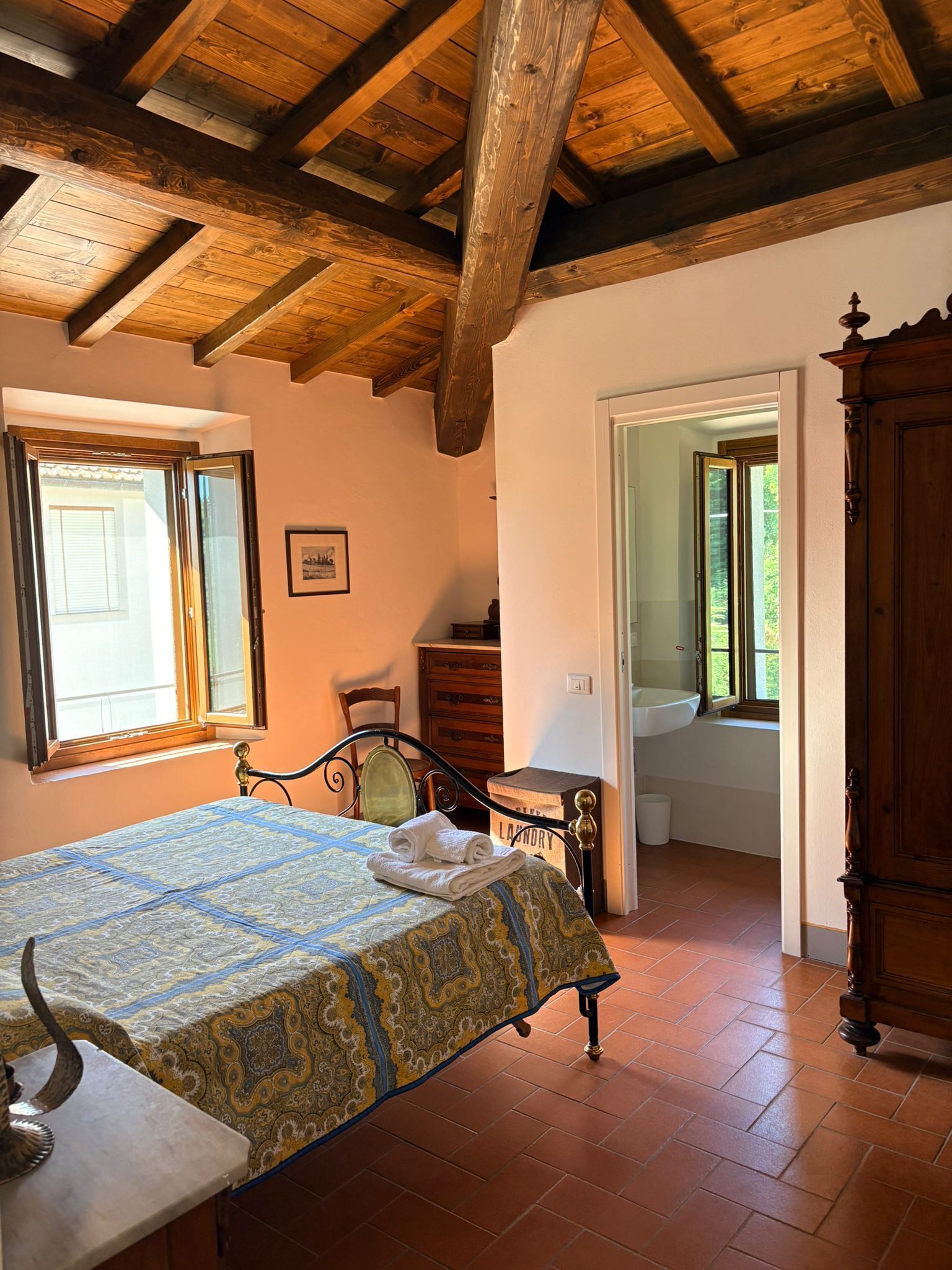A room with a bed, a wooden cabinet, a chair, and a window.