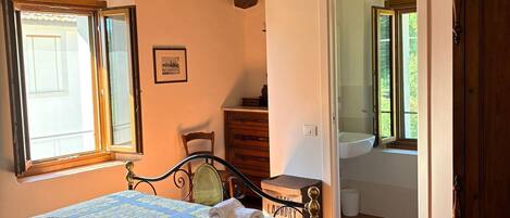 A room with a bed, a wooden cabinet, a chair, and a window.