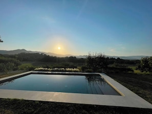 A rectangular swimming pool with a clear view of the surrounding landscape, including distant hills and a clear sky.