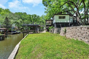 A riverside property with a dock, a stone wall, and a house with multiple levels.