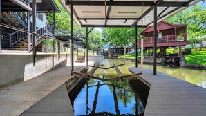 A covered outdoor area with a water feature, wooden benches, and a red building with a balcony. - Riverview Hideaway: Waterfront & Boat Lift! (Kingsland)