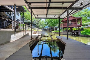 A covered outdoor area with a water feature, wooden benches, and a red building with a balcony.