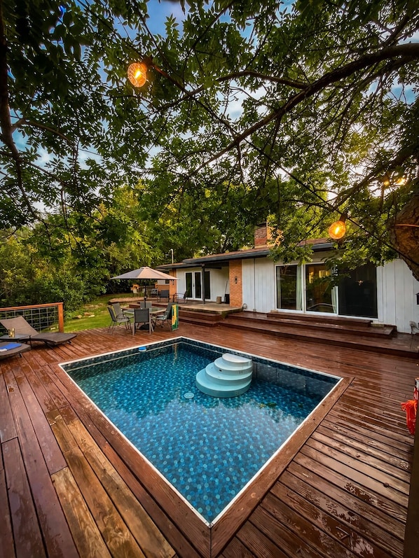 A swimming pool with a wooden deck, a covered outdoor seating area, and a house in the background. - Pool Home-World Cup-10 Min AT&T Stadium-Sleeps 10 (Grand Prairie)