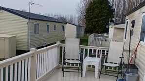 A covered outdoor area with a white railing, two chairs, and a small table.