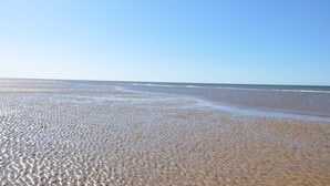 A beach with a wide expanse of sand and gentle waves.