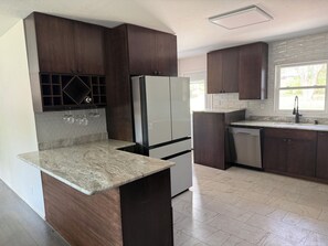 A kitchen with dark wooden cabinets, a white refrigerator, a granite countertop, and a tiled backsplash. - Lovely 3-bedroom house in Colorado Springs. Close to MANY attractions! (Colorado Springs)