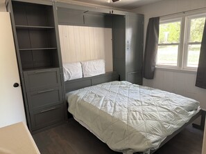 Et soveværelse med seng, indbygget skab og et vindue.