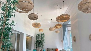 A spacious lounge area with wicker pendant lighting, wooden furniture, and large windows. - Sentido Marillia Hammamet  (Hammamet)