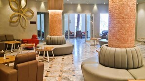 A lobby with seating areas, a decorative wall piece, and a large pillar. - Sentido Marillia Hammamet  (Hammamet)