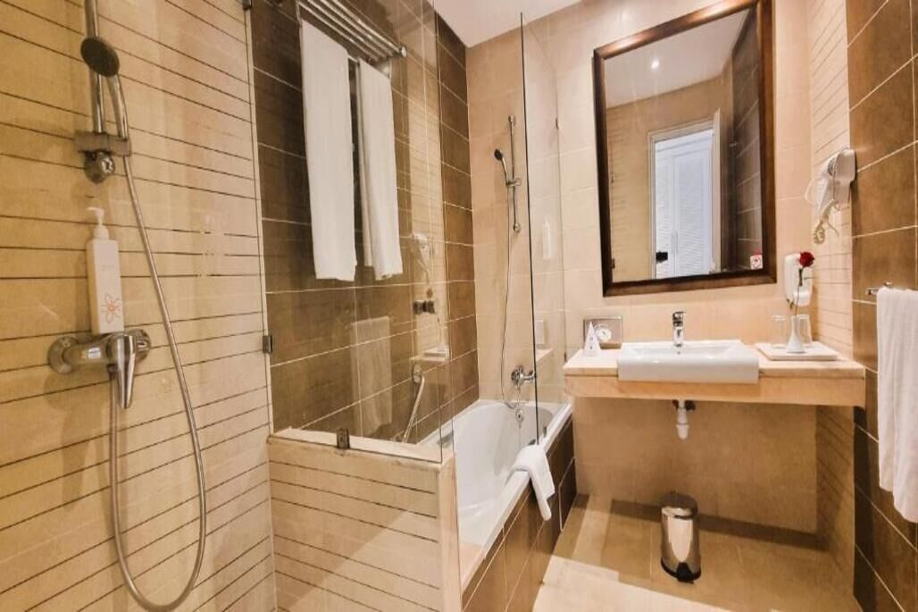 Un baño moderno con ducha de vidrio, bañera, lavamanos y espejo.