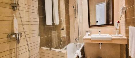 Un baño moderno con ducha de vidrio, bañera, lavamanos y espejo.