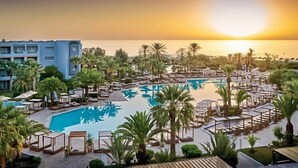 A resort pool area with lounge chairs, palm trees, and a building in the background. - Sentido Marillia Hammamet  (Hammamet)