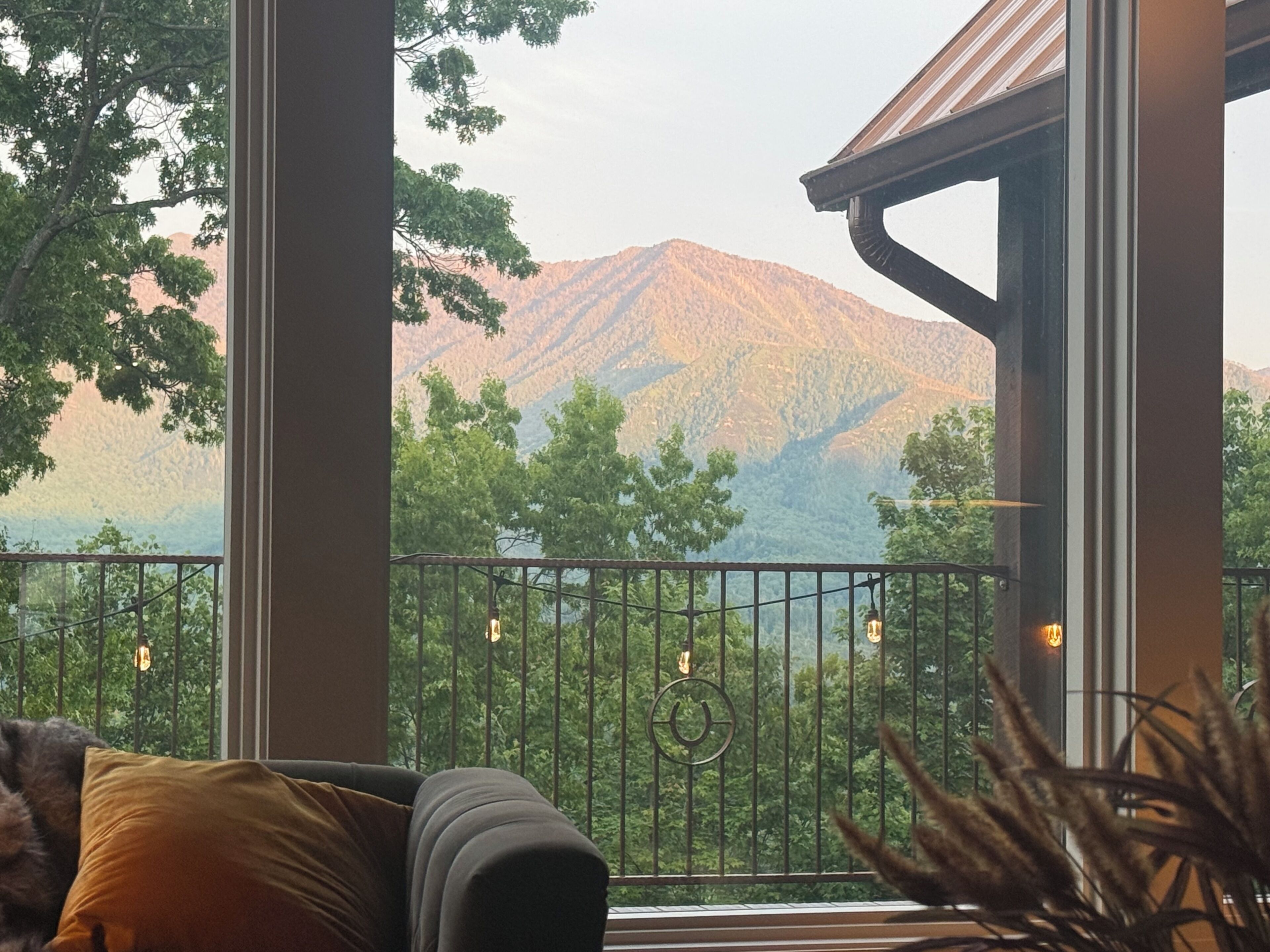 Ein Balkon mit Blick auf Berge, einem Geländer und einer Couch mit Kissen.