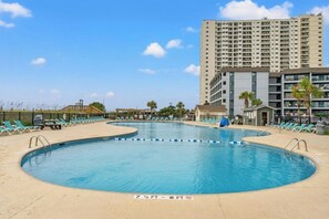 A swimming pool with lounge chairs and a tall building in the background. - MB Five Seasons 6203- 1BR Close to Beach (Myrtle Beach)