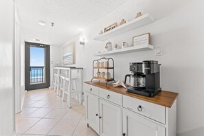 Eine moderne Küche mit Kaffeemaschine, weißen Schränken und Meerblick.
