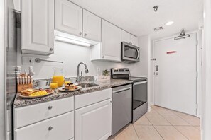 A modern kitchen with white cabinets, a stainless steel microwave, and a dishwasher. - Oceanfront Buena Vista 703- 2BR- Outdoor Pool (North Myrtle Beach)
