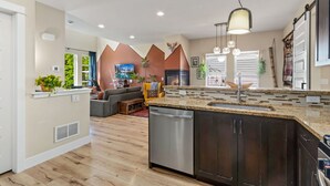 A modern kitchen with a dishwasher, a built-in oven, and a large island with a sink. - Casa Tierra Walk to Old Town via Poudre Trail (Fort Collins)