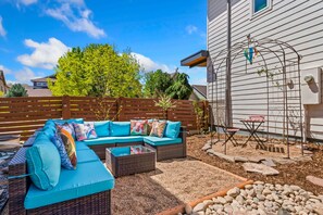 A patio with a sectional sofa, a wicker table, and a birdcage.