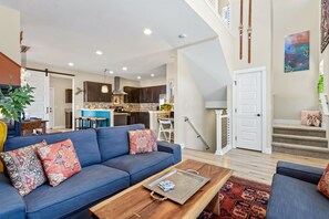 A modern living room with a sofa, coffee table, and a staircase leading to a second floor.