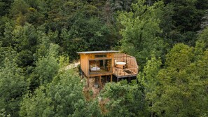 A wooden cabin with a glass enclosure, a hot tub, and a deck. - Les Coteaux Lodges & Expériences (Laparade)