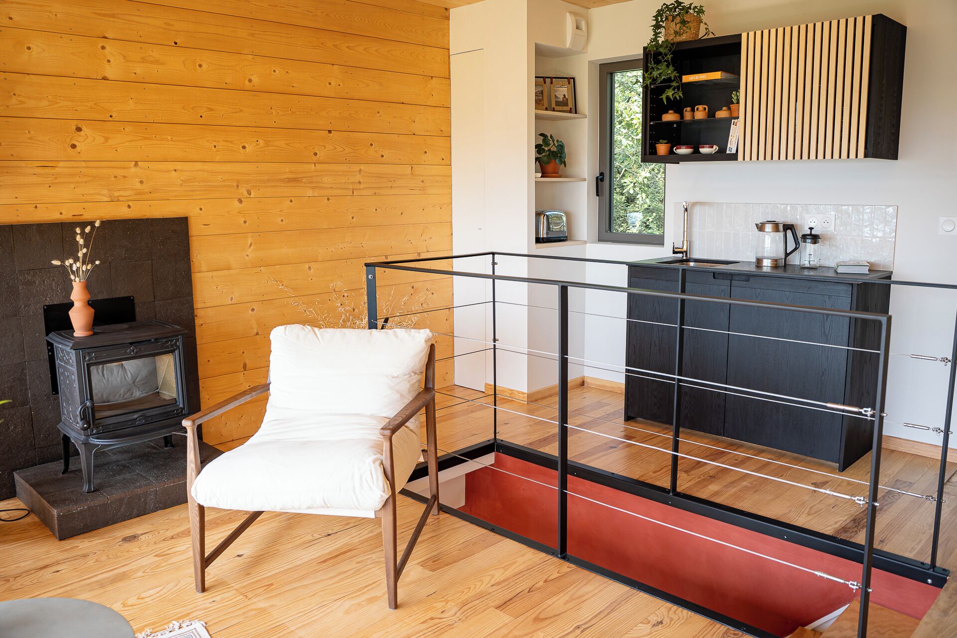 Una cocina moderna con encimera negra, suelo de madera y un estante empotrado con elementos decorativos.