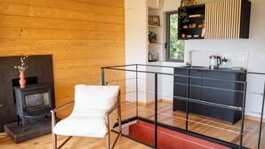 A modern kitchen with a black countertop, wooden flooring, and a built-in shelf with decorative items.
