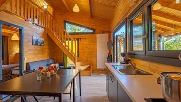 A wooden interior with a dining area, kitchen, and staircase.