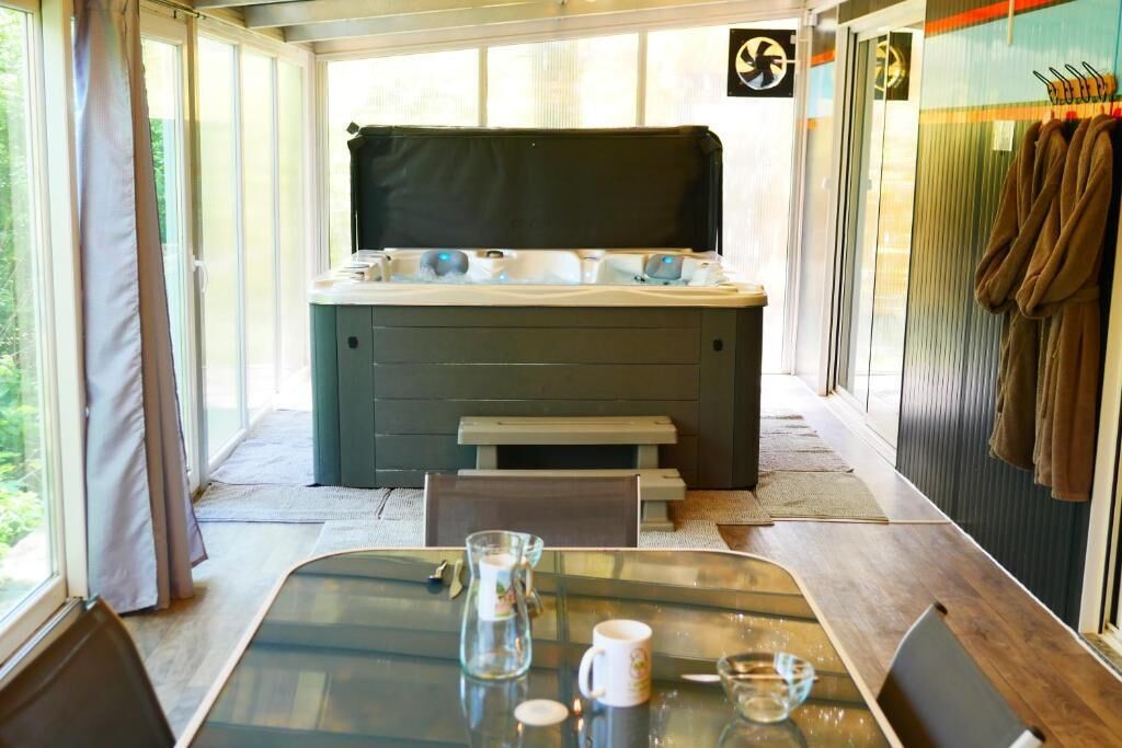 Ein Zimmer mit Whirlpool, einem Tisch mit Gläsern und einer Karaffe sowie einer Bank.