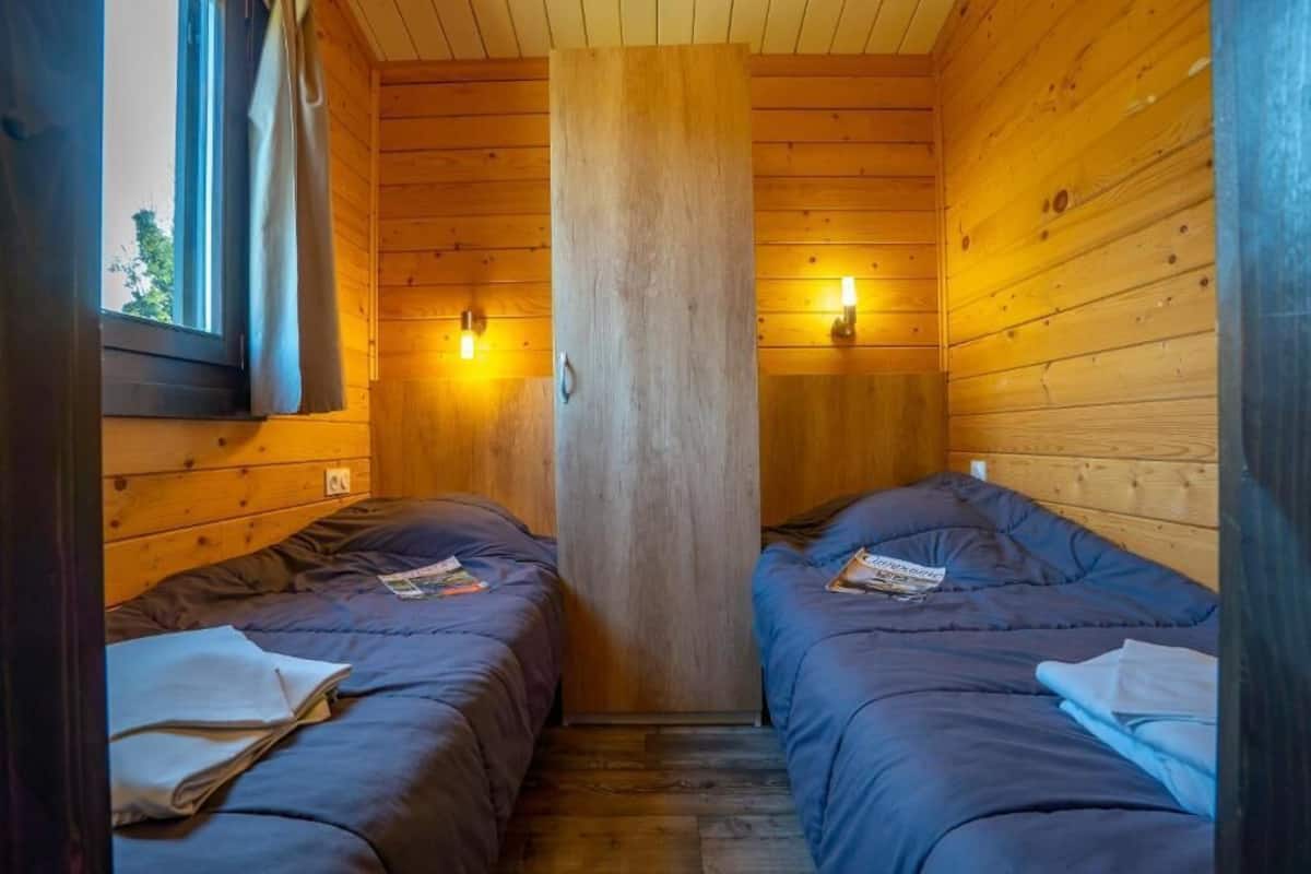 Eine Holzhütte mit zwei Betten, einem Fenster und Wandleuchten.