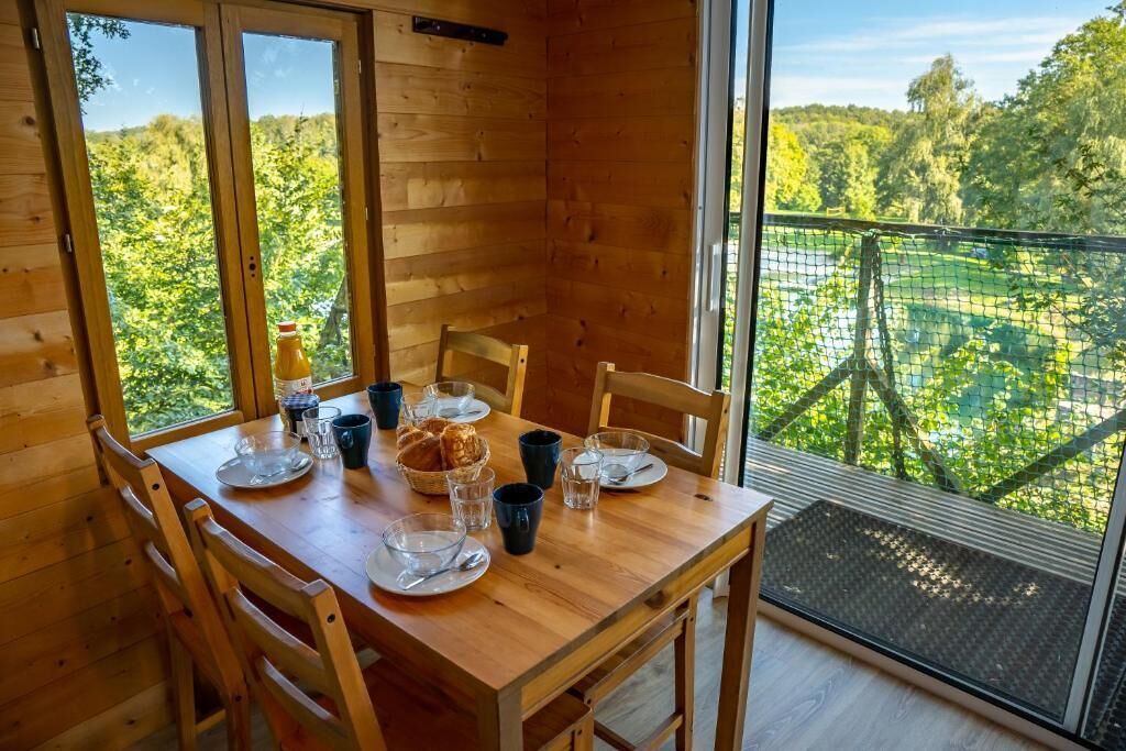 A wooden dining table with chairs, a basket of bread, and clear glasses.