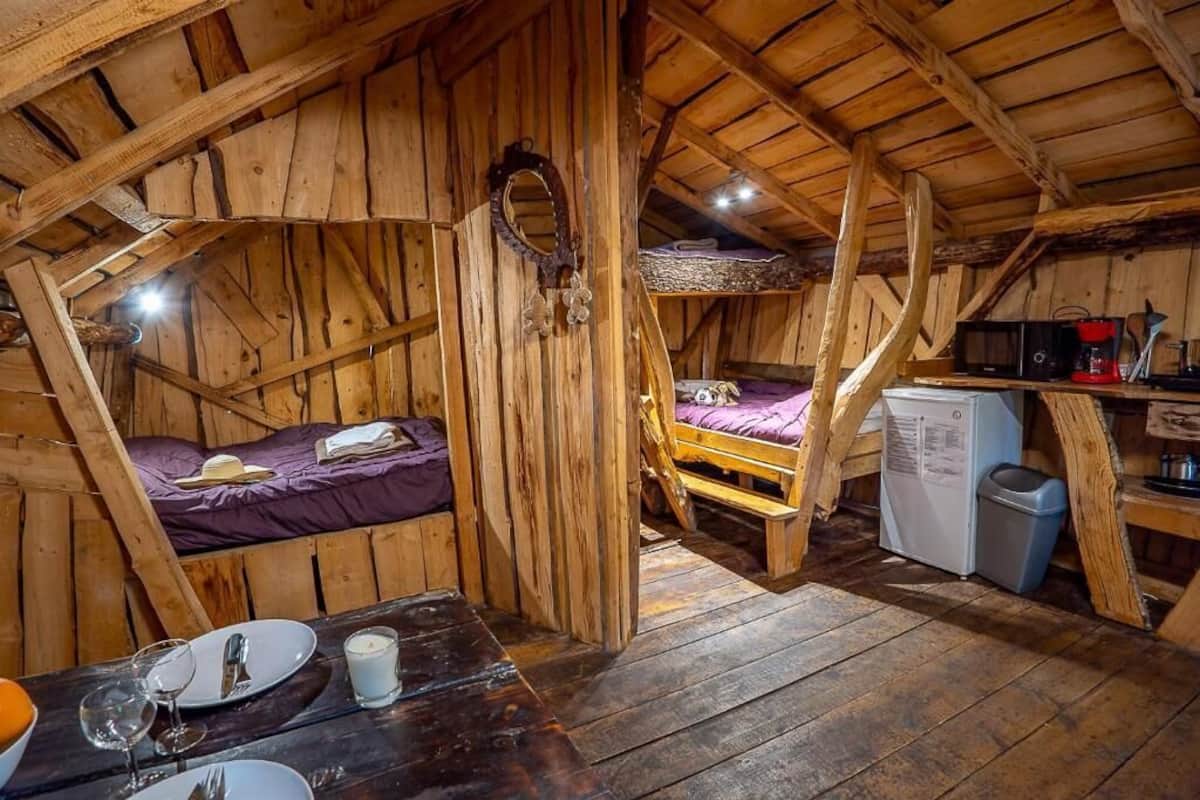 Ein rustikaler Holzraum mit Schlafkoje, einem kleinen Tisch mit Tellern und Gläsern, einer Mikrowelle und einem Mülleimer.