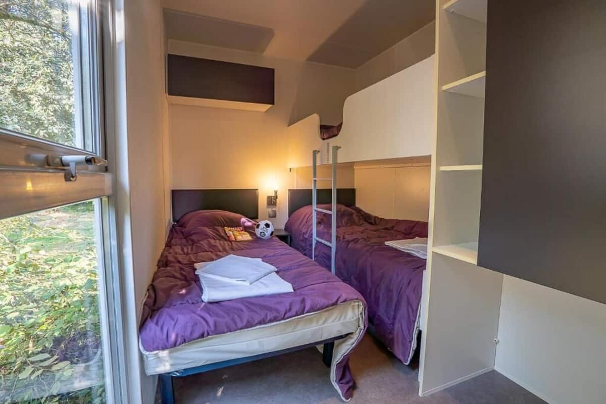 Ein Schlafzimmer mit zwei Betten, einem Fenster und einem Einbauschrank.