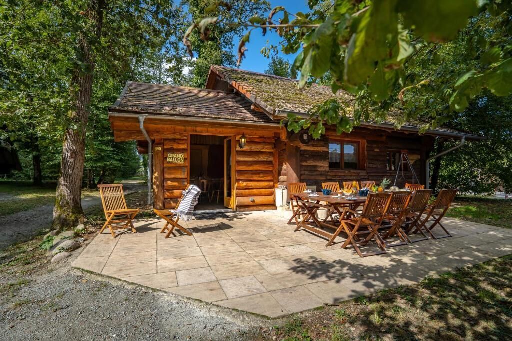 Eine Blockhütte mit Essbereich, einer Veranda und einem Schild, das sie als Gästehaus kennzeichnet.