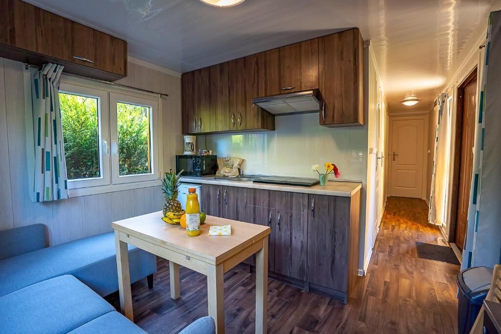 A compact kitchen with wooden cabinets, a dining table, and a view of the outdoors.