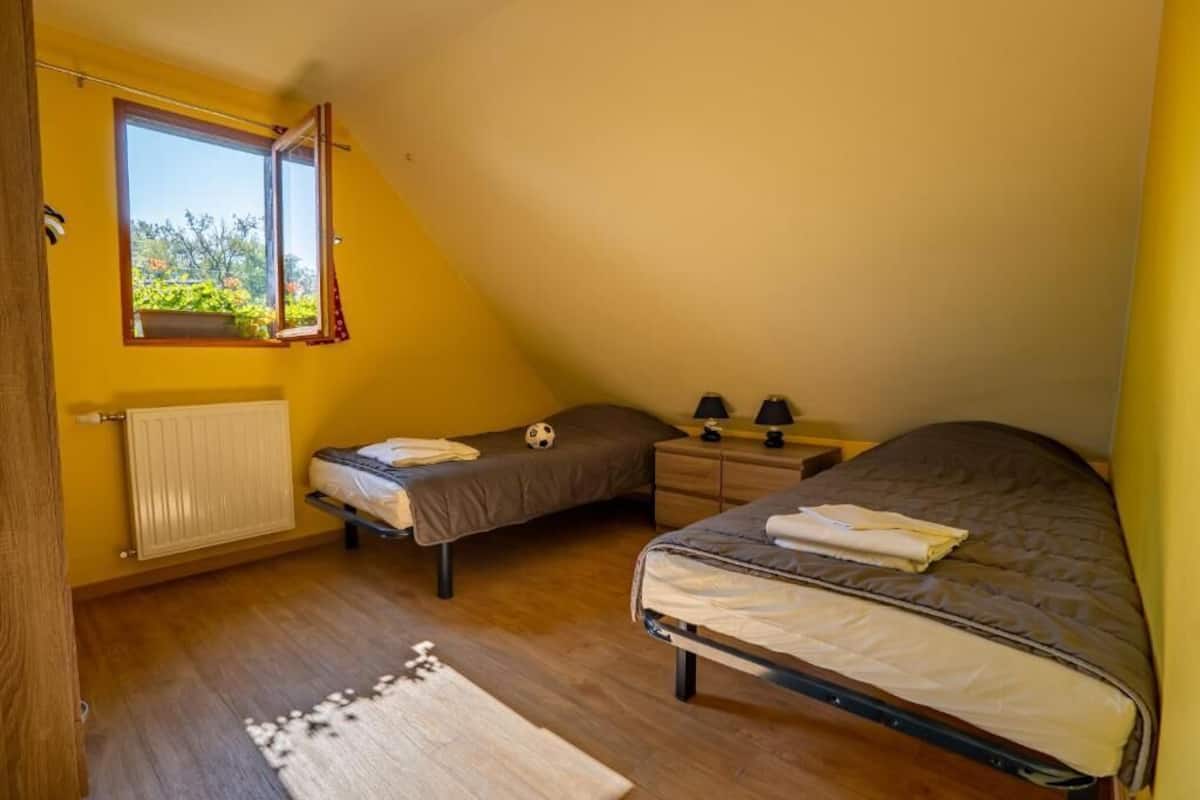 Ein Schlafzimmer mit zwei Betten, einem Fenster, einer Heizung und einem Nachttisch mit Lampen.