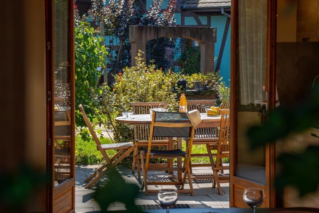 En terrasse med et bord, stole, en flaske og et glas.