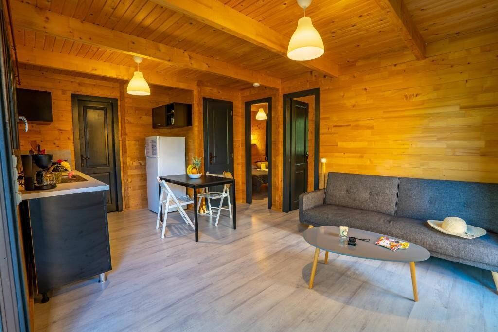 A wooden interior with a dining area, sofa, and kitchen.
