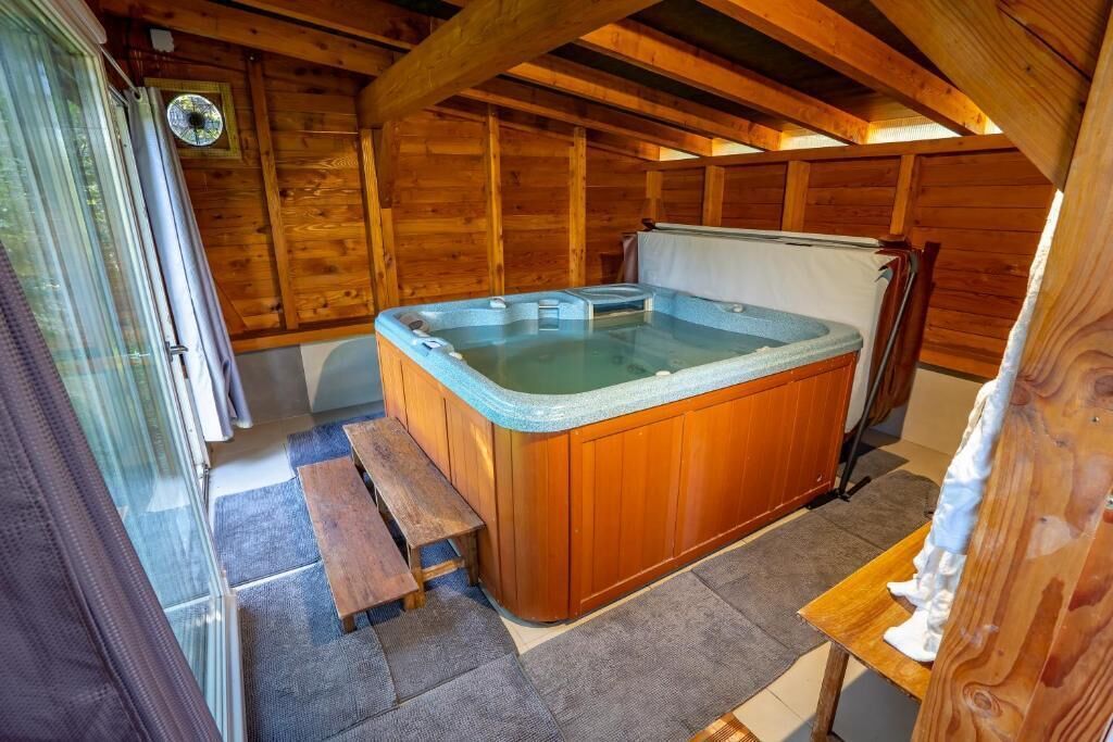 Een houten chalet met een hottub, een bank en een kleine tafel.