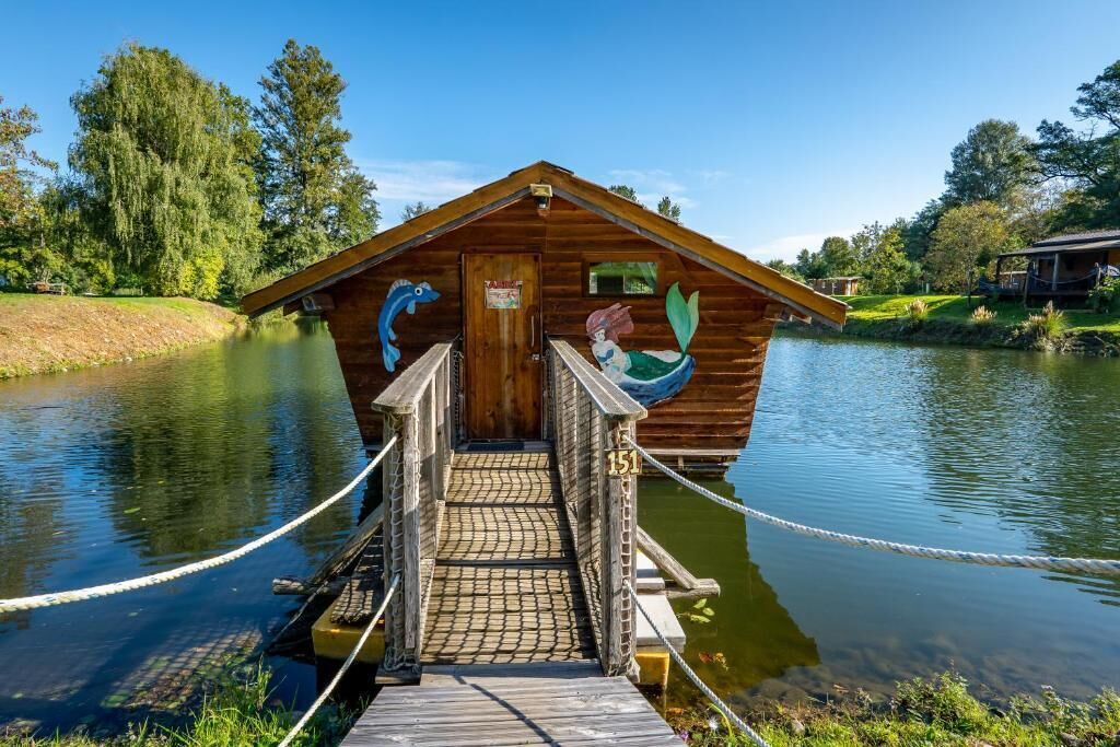 A wooden cabin with a dock, a sign, and a number 151.