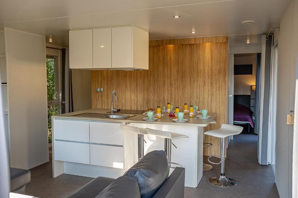 Una cocina moderna con una isla central, taburetes de bar y un comedor.