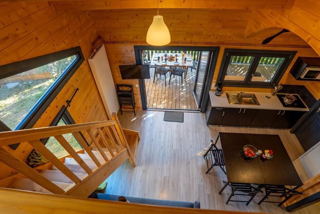 Uma cabana de madeira com área de jantar, cozinha e escada que leva a um mezanino.