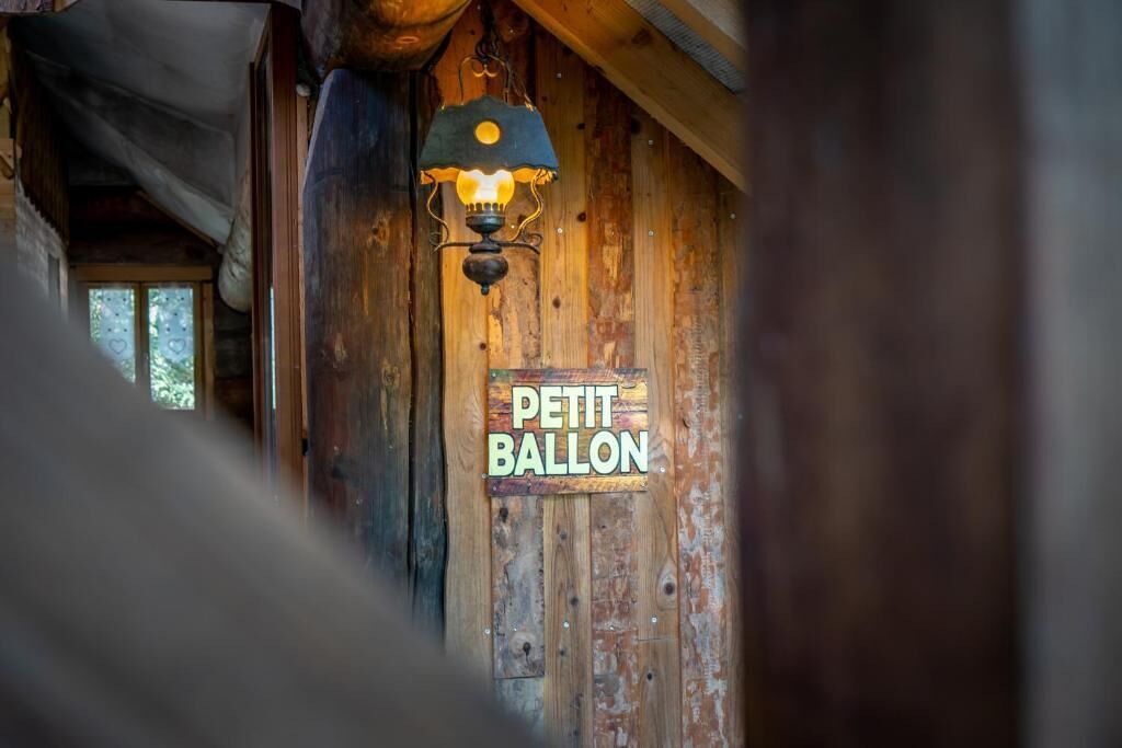 A rustic wooden wall with a hanging light fixture and a sign that reads 'PETIT BALLON'.
