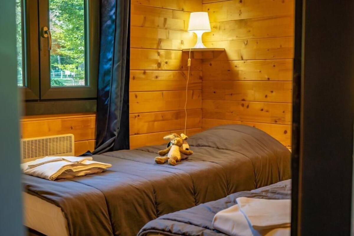 Ein Zimmer mit Holzwandverkleidung, einem Bett, einer Lampe und einem Fenster.