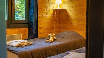 A wooden-paneled room with a bed, a lamp, and a window.