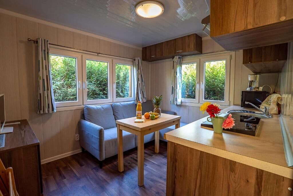 Una cocina funcional con comedor, armarios de madera y ventana con vista a follaje.