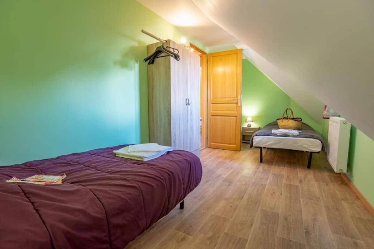 Ein Schlafzimmer mit Bett, Nachttisch, Kleiderhaken, Kleiderschrank und einem kleinen Tisch mit Korb.