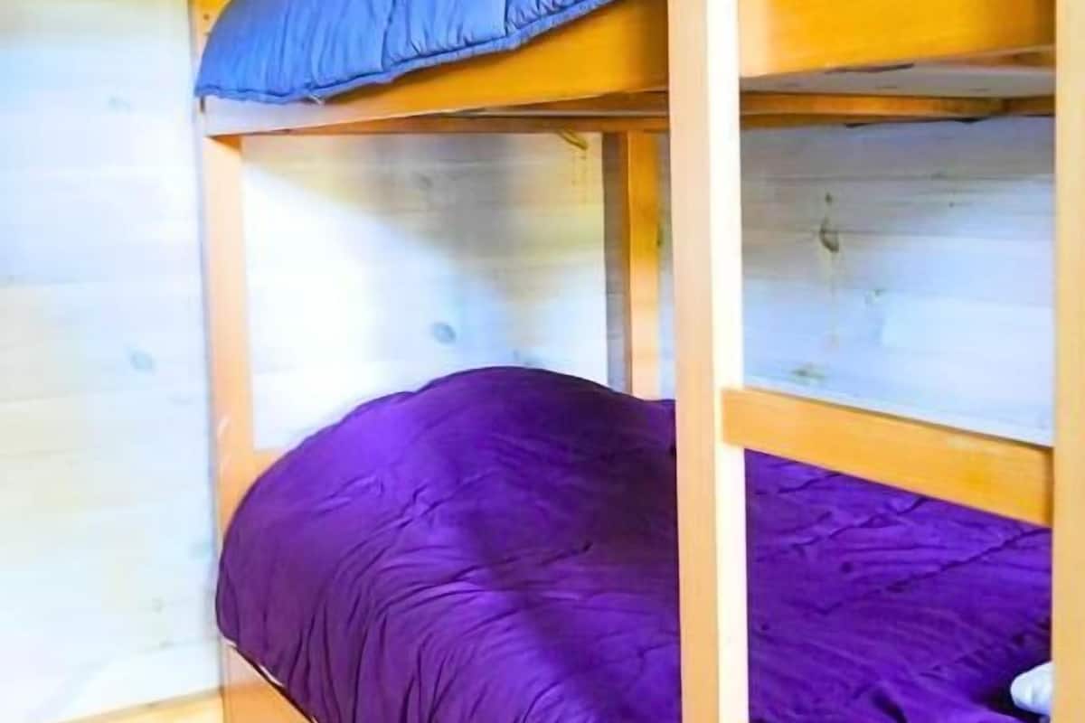 Ein Etagenbett mit einer violetten Matratze und einem blauen Kopfkissen.